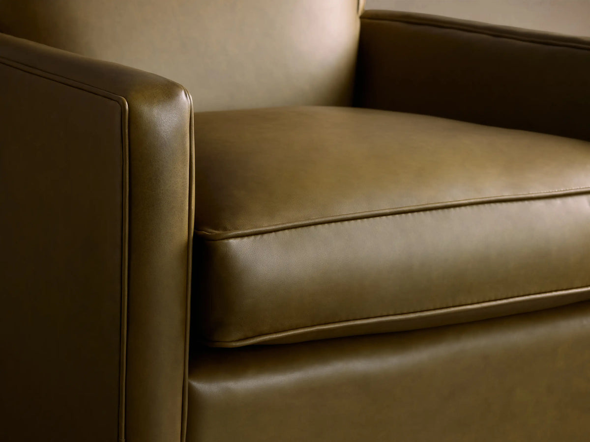 Front-facing Rudy Leather Swivel Chair in olive green leather, featuring square arms & a visible black swivel base on a wood floor.
