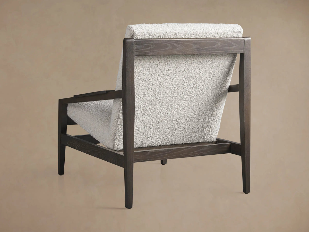 Sarlow Chair, close-up angled view showing dark wood frame and light cream, textured fabric cushions.
