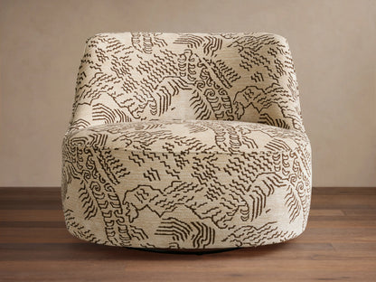 Sonny Swivel Chair upholstered in cream fabric with a dark brown abstract wavy pattern, angled left on wood floor.