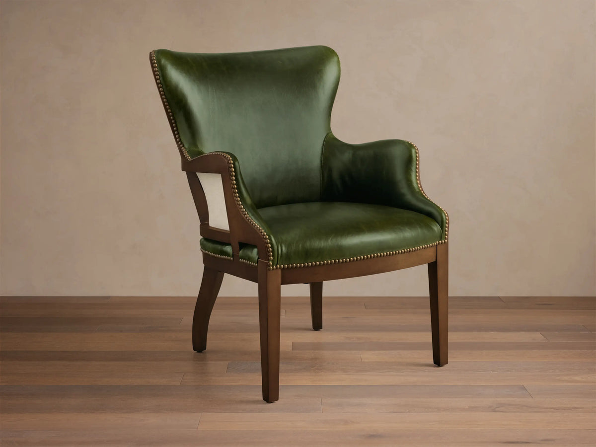 Front view of the green leather Tilly Leather Chair with a dark wooden frame and brass nailhead detailing.
