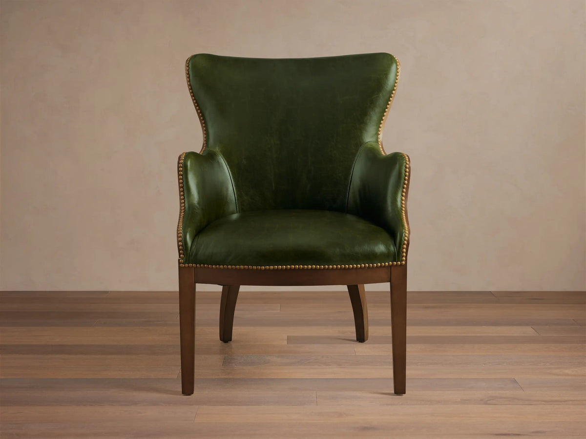 Front view of the green leather Tilly Leather Chair with a dark wooden frame and brass nailhead detailing.