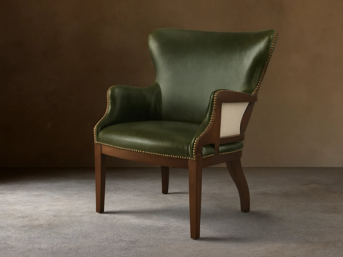 Front view of the green leather Tilly Leather Chair with a dark wooden frame and brass nailhead detailing.
