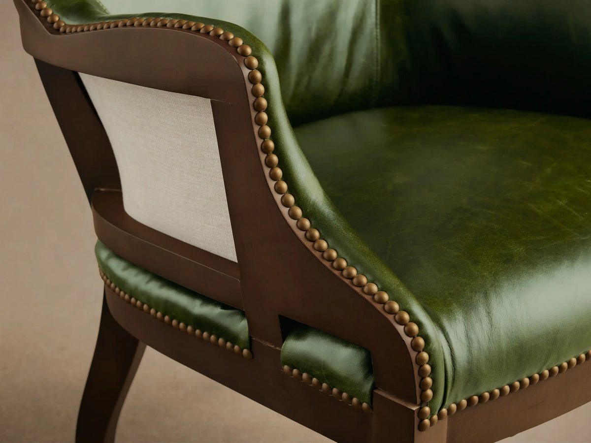 Front view of the green Tilly Leather Chair with brass nailhead detailing and dark wooden legs.