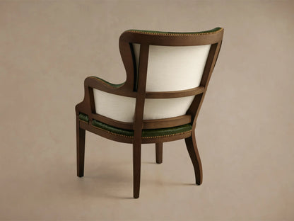 Close-up of the Tilly Leather Chair showing its green leather upholstery, dark wood frame, brass nailhead trim, and light fabric side panel.