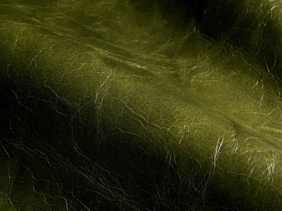 Rear view of the Green Tilly Leather Chair, with a dark wood frame, off-white fabric back, and brass nailhead details.