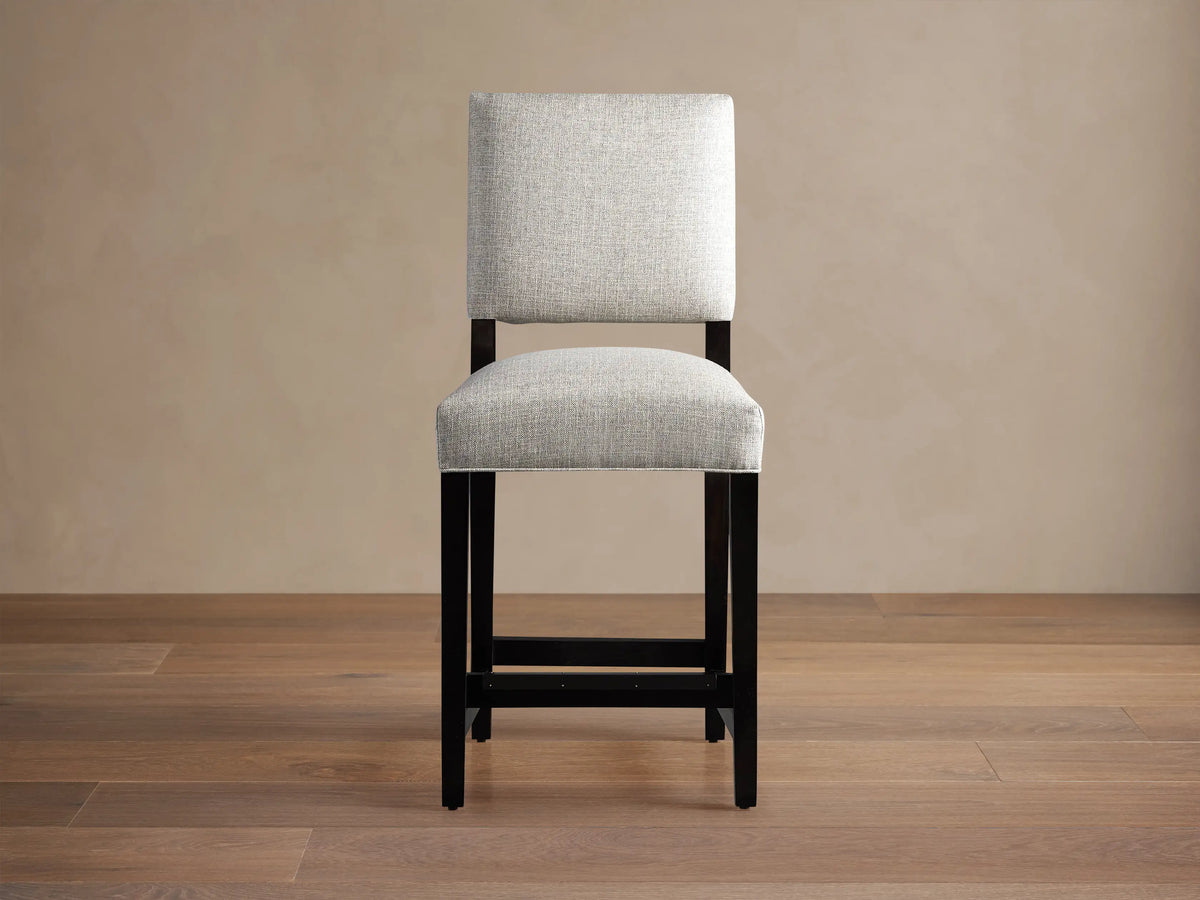Torino Stool with light grey upholstered seat and back, dark wood frame, standing on a wooden floor.
