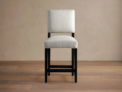 Torino Stool with light grey upholstered seat and back, dark wood frame, standing on a wooden floor.