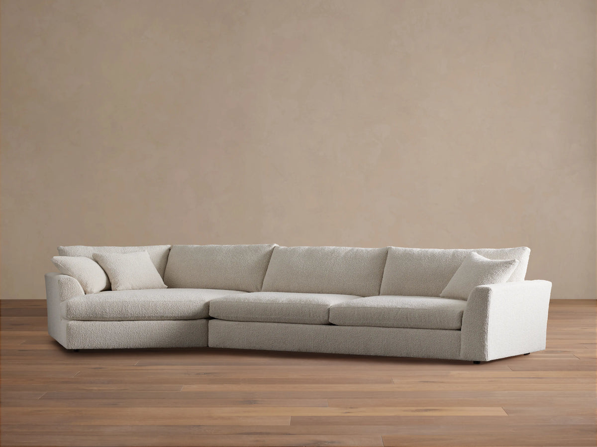 Vernon Two-Piece Cuddle Chaise Sectional, L-shaped, in cream boucl?? fabric, with plush cushions, on a wood floor.