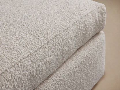Vernon Ottoman, rectangular, upholstered in plush, off-white textured fabric, sitting on a wooden floor against a light wall.
