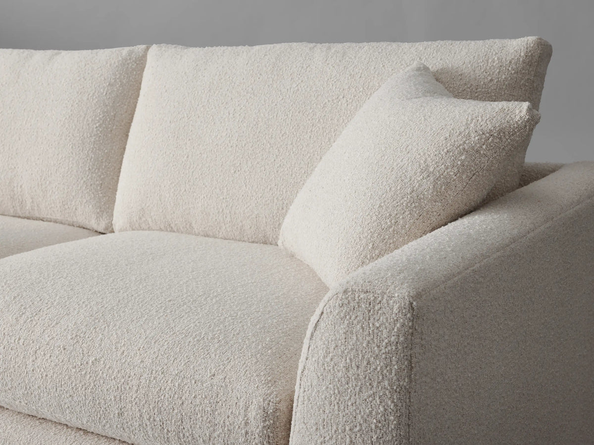 Vernon Sofa, an off-white two-seater sofa with textured fabric, two back cushions, two throw pillows, front-left view.