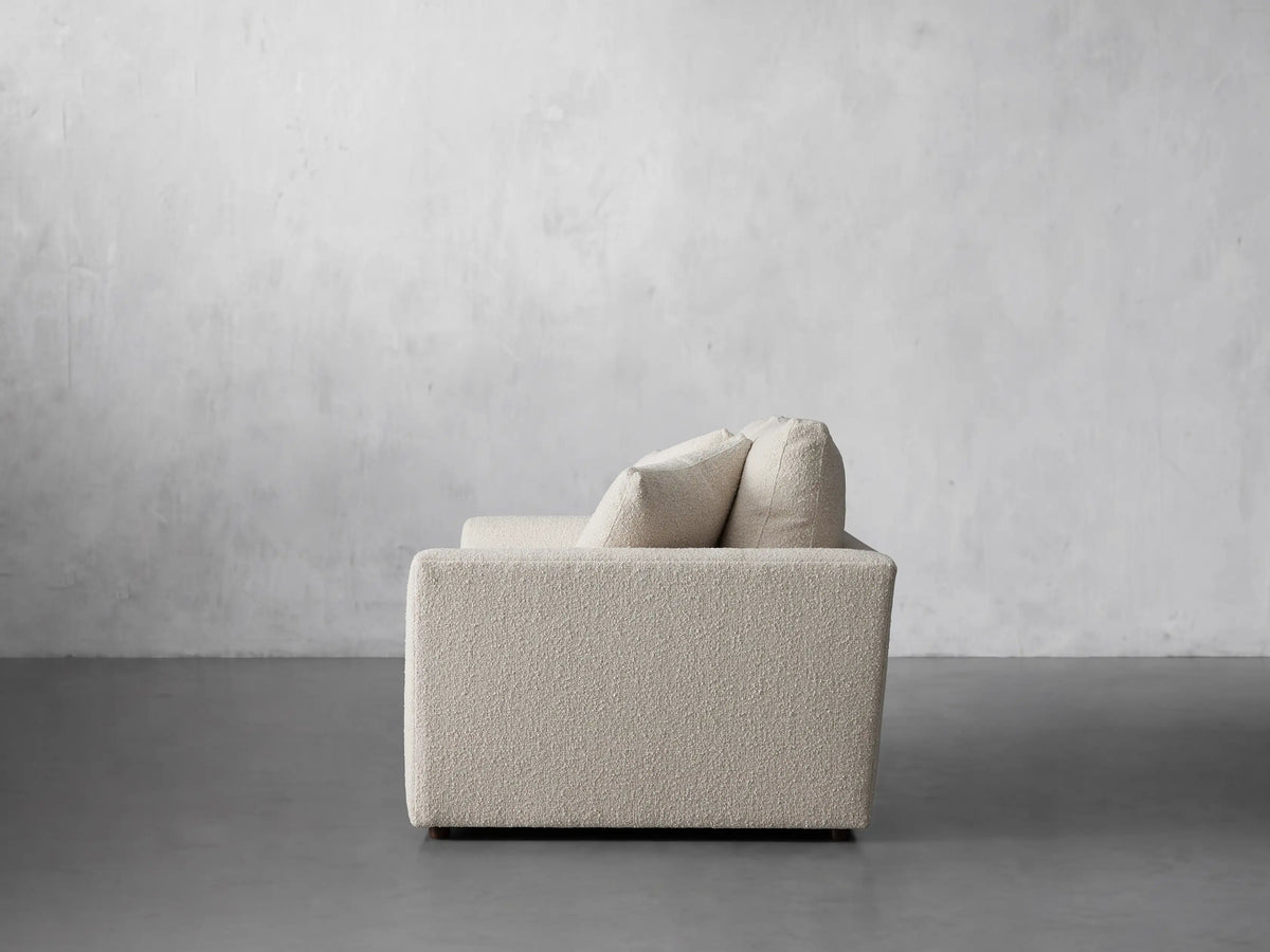 Close-up of an off-white Vernon Sofa with textured fabric, showing two back cushions, seat, armrest, and a throw pillow.