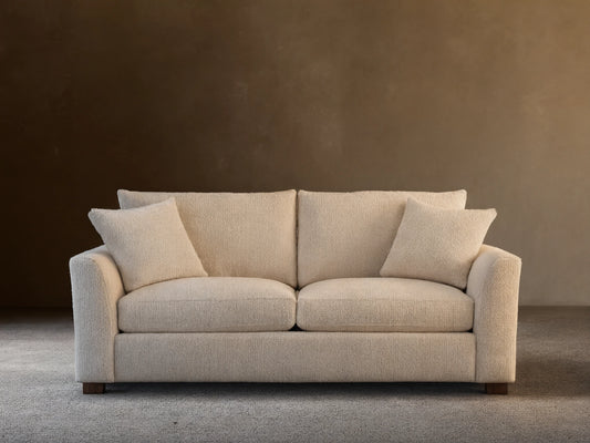Front view of a Vernon Sofa, a cream bouclv© two-seater couch, featuring two back cushions and two matching throw pillows.