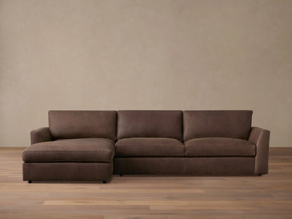Brown Vernon Leather Two-Piece Chaise Sectional on wooden floor; left-side chaise, right-side three-seat sofa; neutral wall backdrop.