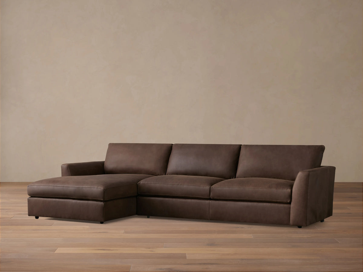 Brown Vernon Leather Two-Piece Chaise Sectional on wooden floor; left-side chaise, right-side three-seat sofa; neutral wall backdrop.