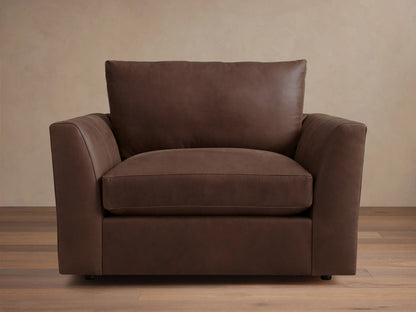 Vernon Leather Chair in dark brown leather, featuring a boxy silhouette with plush cushions and straight armrests, set against a wood floor.