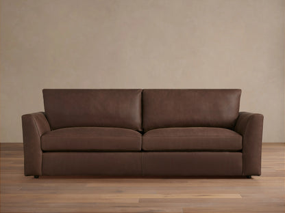 Vernon Leather Sofa featuring a rich brown finish, plush seat cushions, wide armrests, and clean lines, set against a neutral wall.