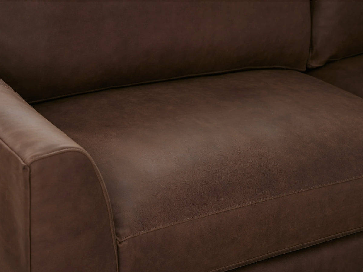 Vernon Leather Sofa close-up showing smooth, rich brown leather upholstery with visible natural variations on seat cushion and armrest.