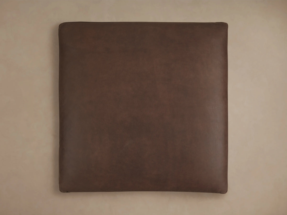 Dark brown, square Vernon Leather Ottoman viewed from above on a neutral background, showcasing its smooth leather texture and soft edges.