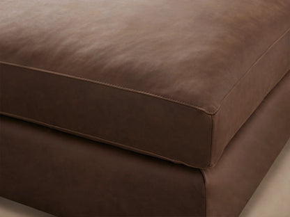 Vernon Leather Ottoman in rich brown leather, showcasing a smooth, cushioned top and precise stitching along the edges.