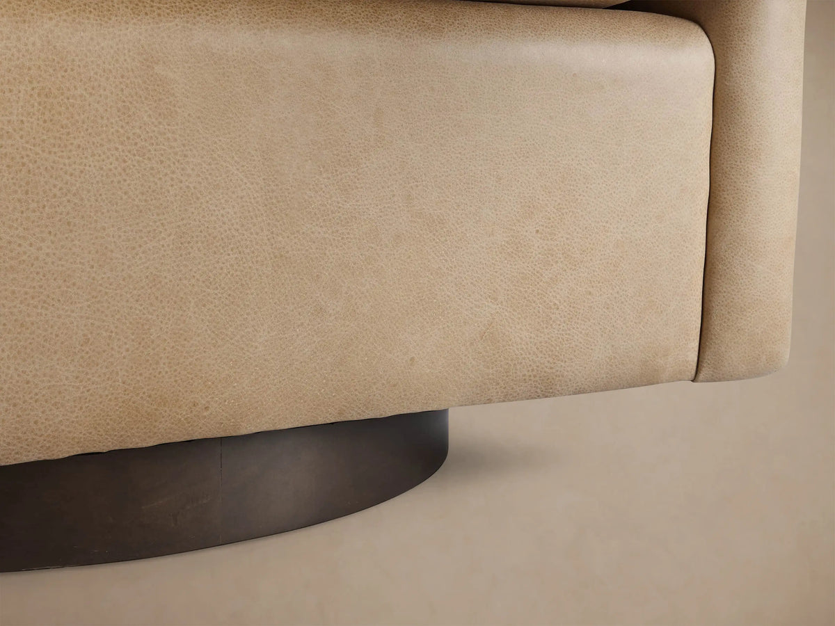 Close-up of Bowan Leather Swivel Chair's curved armrest and back in light tan, textured leather with visible stitching.