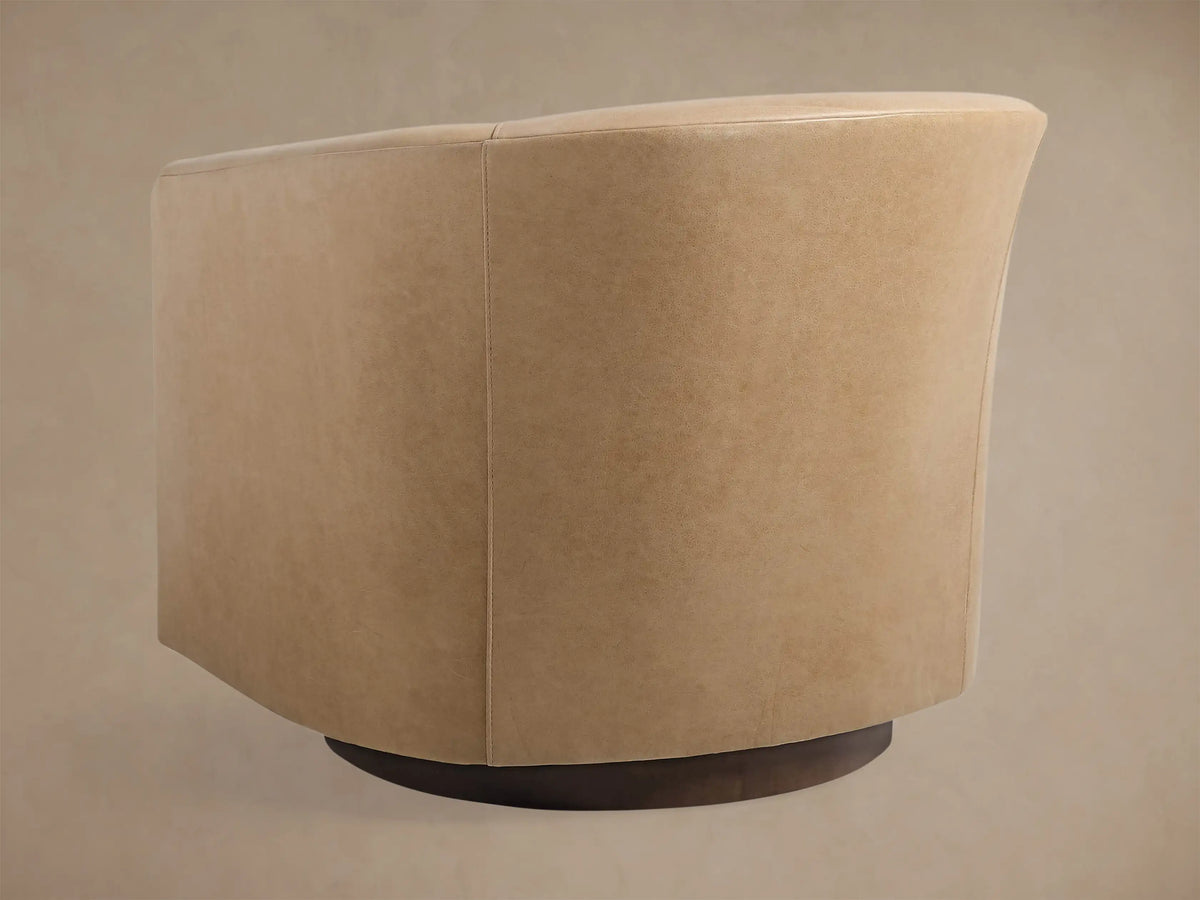 Close-up of Bowan Leather Swivel Chair, showing light tan textured leather upholstery over a dark round swivel base.