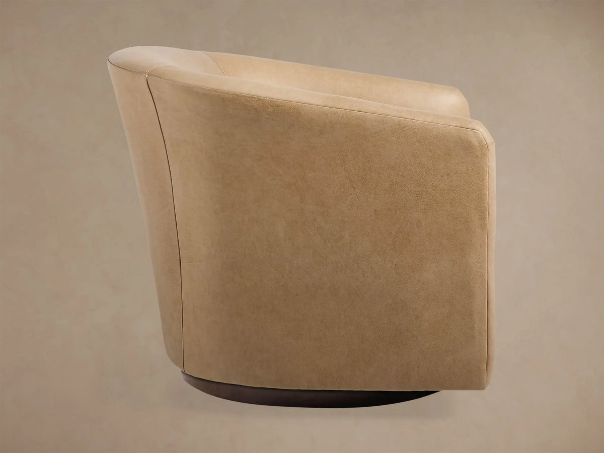 Bowan Leather Swivel Chair, light beige, showing its curved back and right side on a dark round swivel base against a neutral wall.