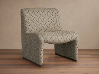 Reyna Chair, armless slipper chair with beige and dark grey leaf pattern fabric, angled on a hardwood floor.