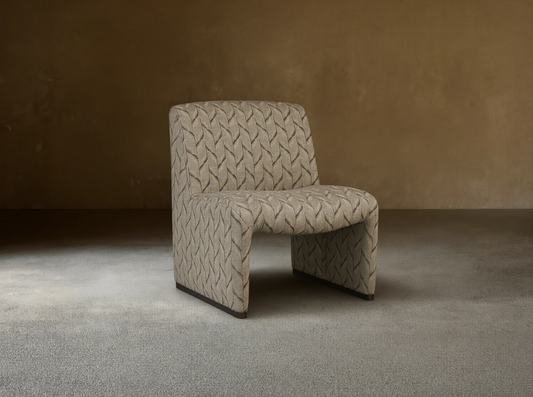 Reyna Chair, armless slipper chair with beige and dark grey leaf pattern fabric, angled on a hardwood floor.