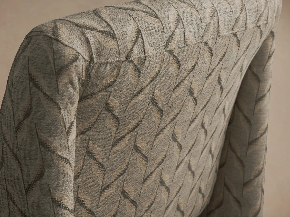 Reyna Chair upholstered in a light beige fabric with an intricate wavy dark pattern, featuring an armless, curved design, facing front.