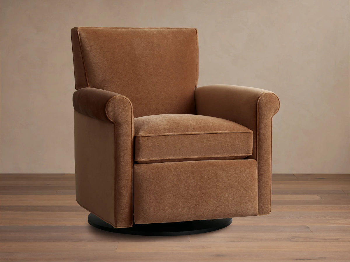 Rudy Rolled Arm Swivel Recliner in cognac velvet, featuring a high back, plush seat cushion, and rounded arms on a wooden floor.