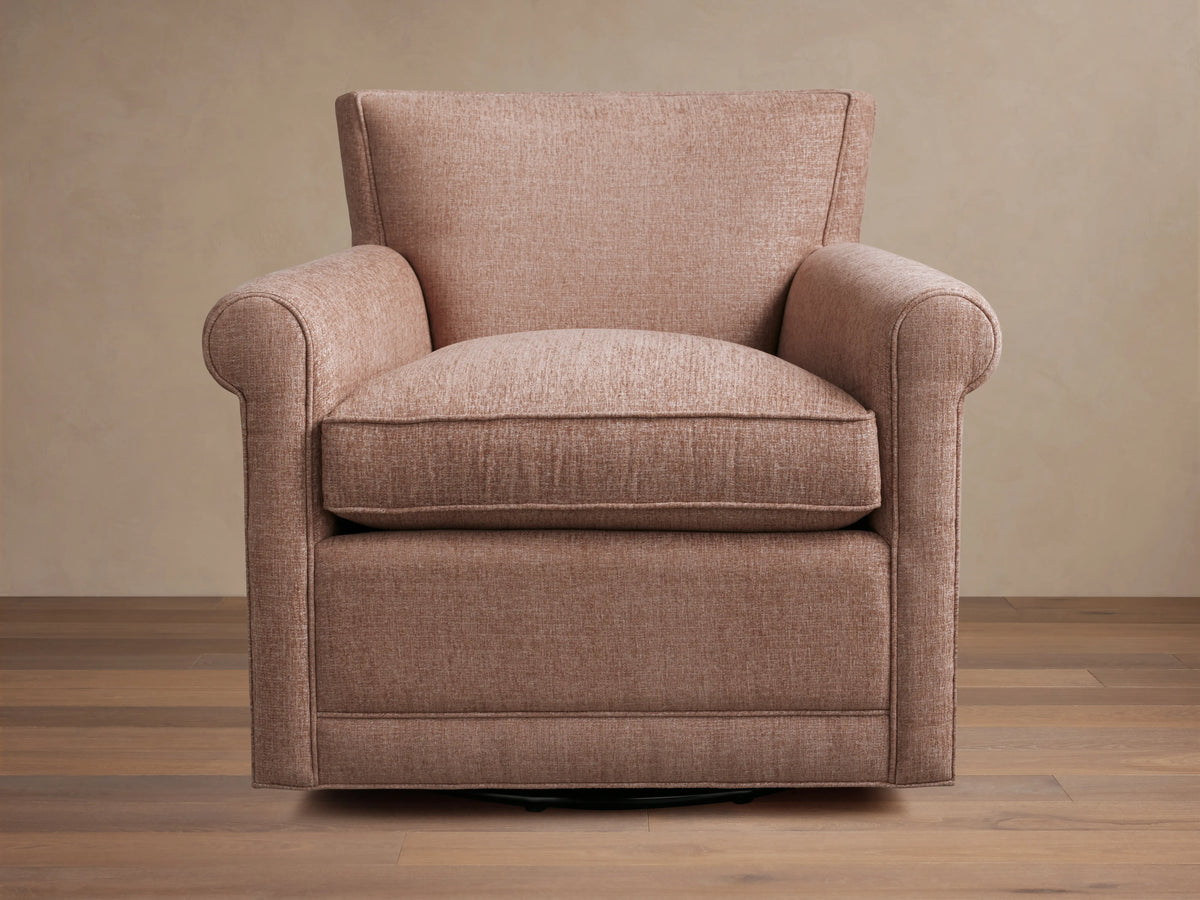 Rudy Rolled Arm Swivel Chair in light brown fabric, featuring rolled arms and a plush cushion on a wooden floor background.