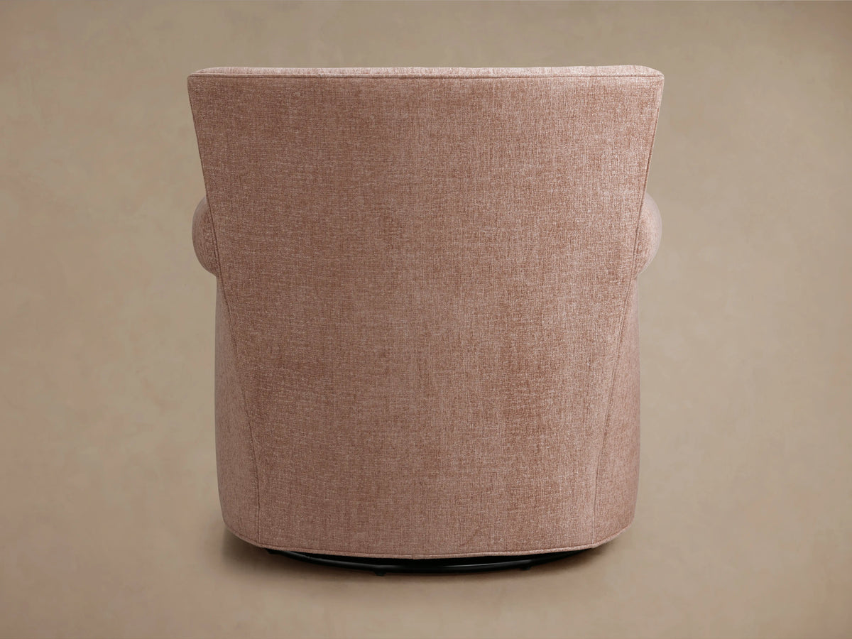 Rudy Rolled Arm Swivel Chair in soft cognac velvet, shown from a back side angle, featuring a smooth, rolled arm and solid swivel base.