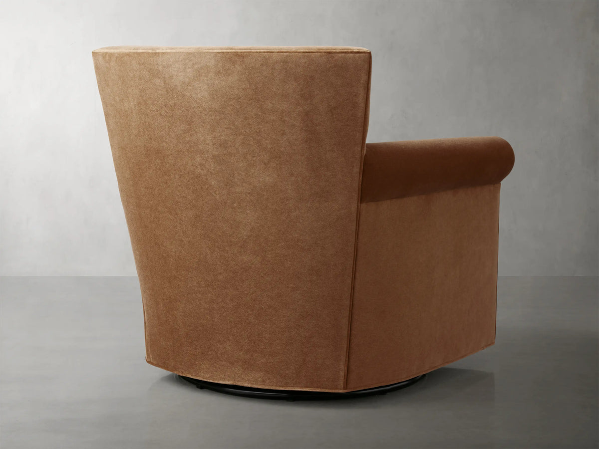 Rudy Rolled Arm Swivel Chair in Banks Cognac fabric, featuring plush seat and backrest, rolled arms, and a swivel base on a gray floor.