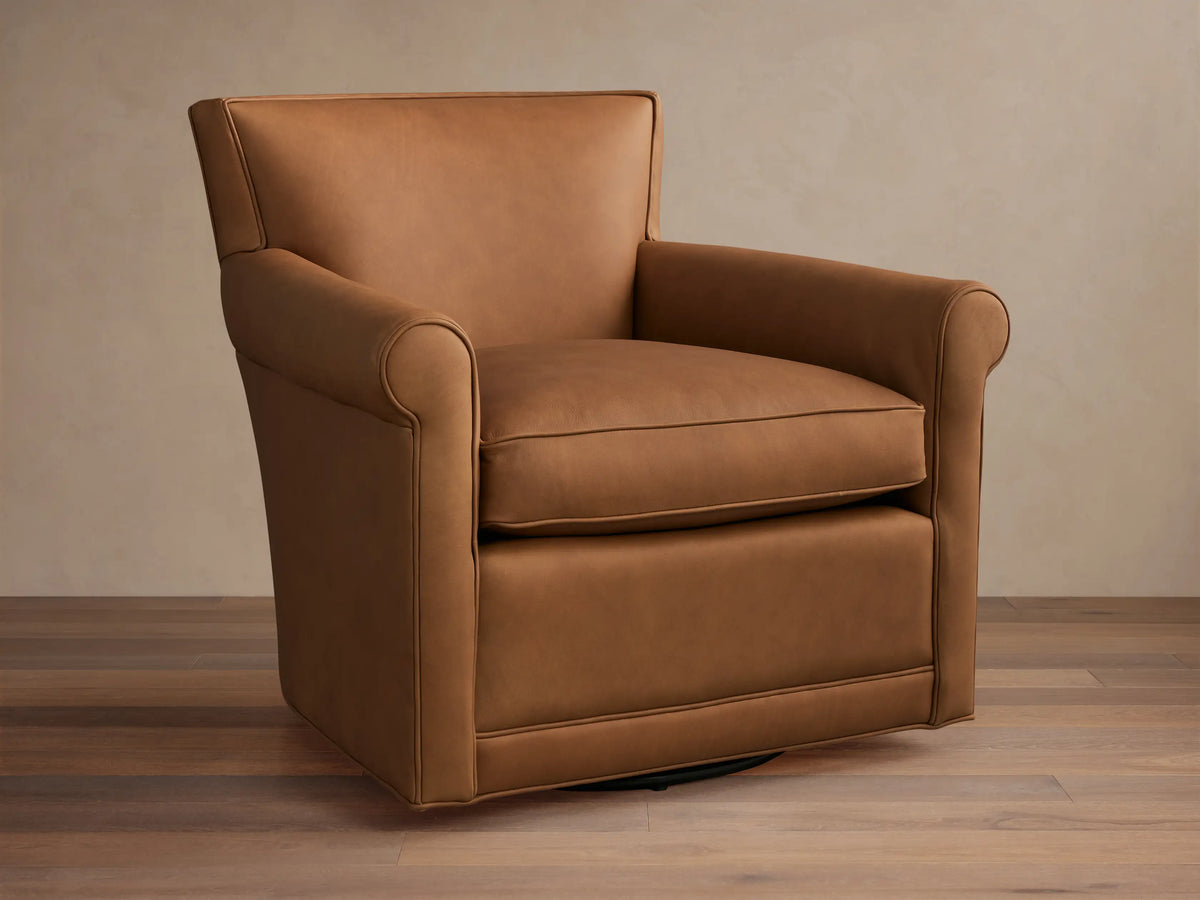 Warm tan leather Rudy Rolled Arm Swivel Chair, featuring rolled arms, a plump seat cushion, and a discreet black swivel base.