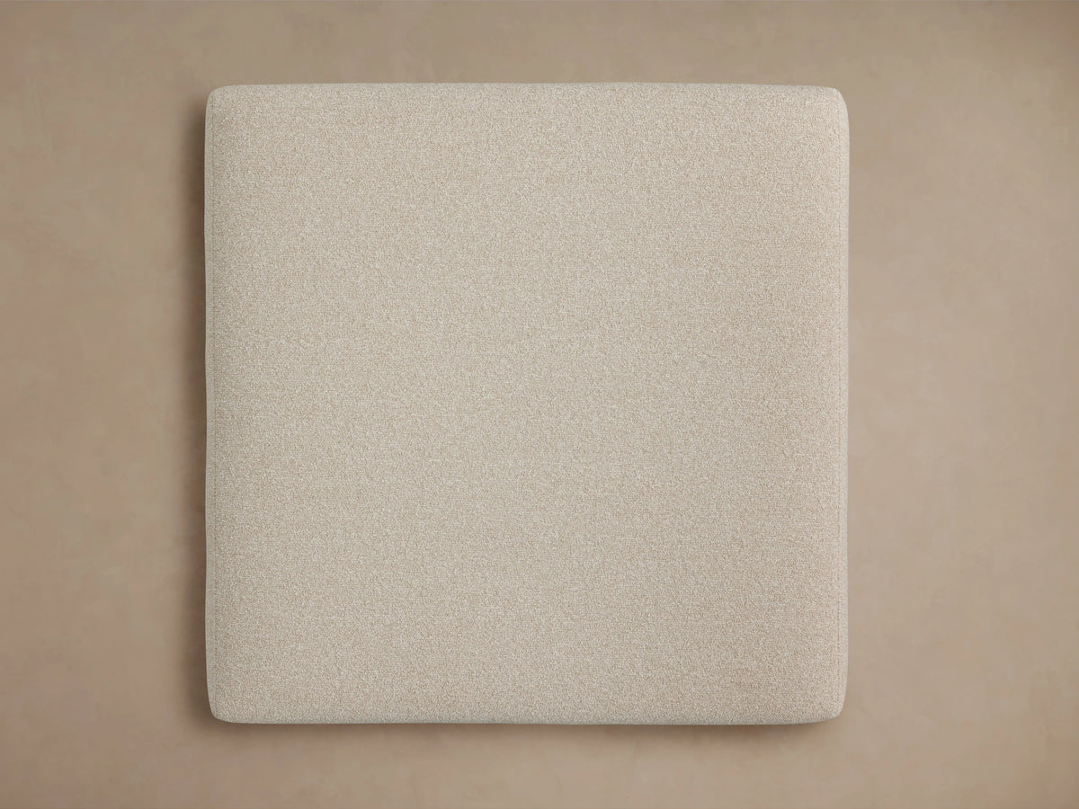 Tilton Ottoman in light beige fabric, featuring a textured surface and sleek black metal legs. The corner view highlights its minimalist design.