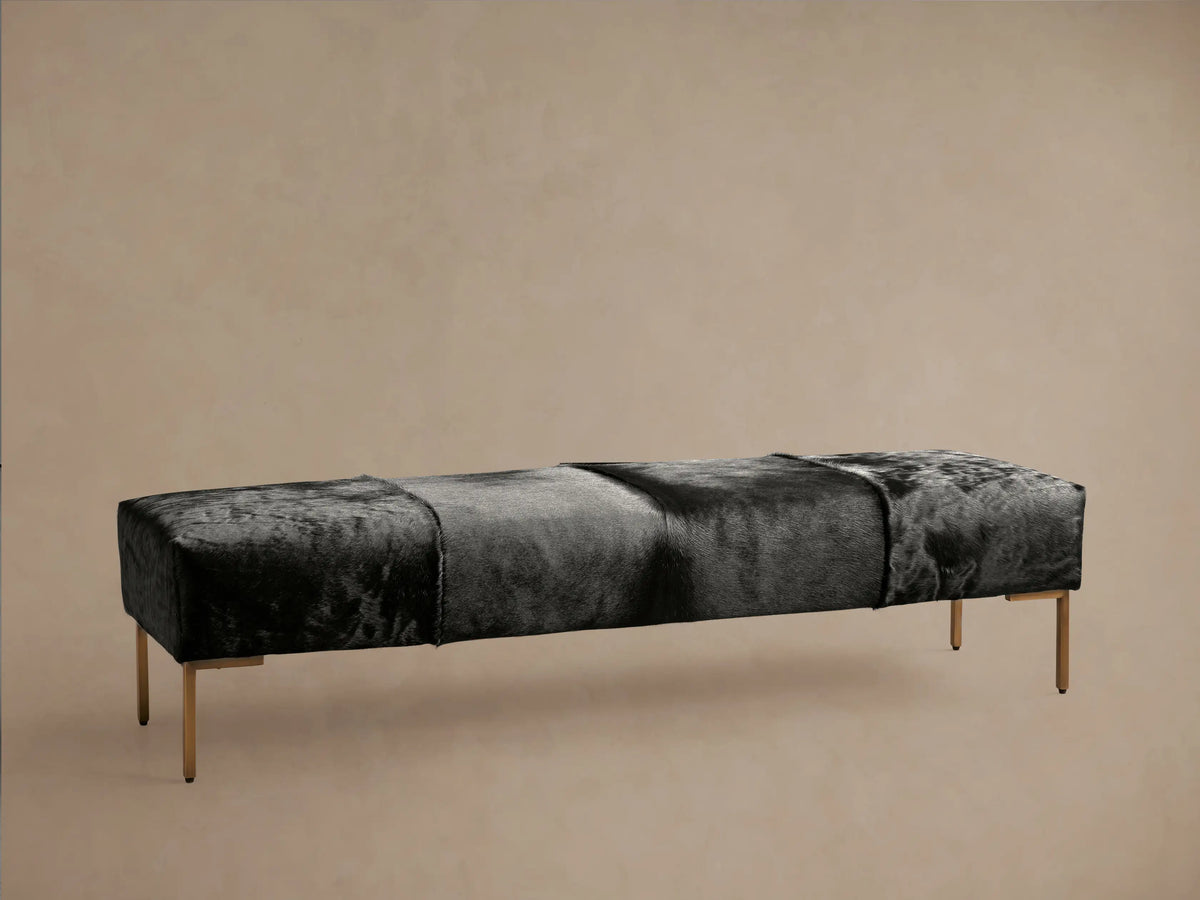 Tilton Hair on Hide Bench with natural, undyed leather in varying shades of brown. Rectangular shape on solid black metal legs, set on wooden floor.