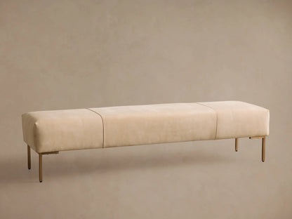 Tilton Leather Bench: a long, rectangular creamy beige upholstered bench with three sections, on slender gold metal legs, wood floor.