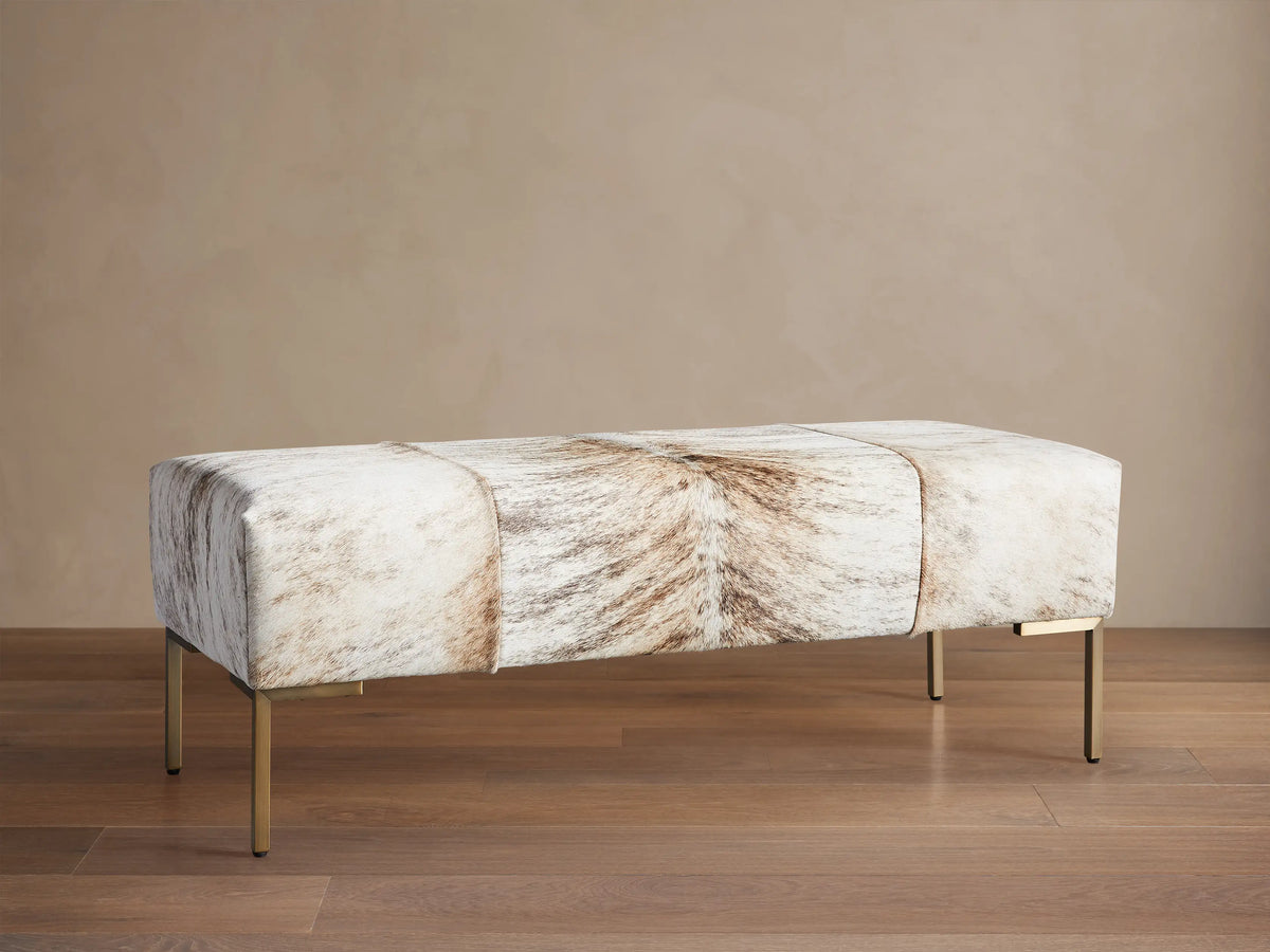 Tilton Hair on Hide Ottoman, a long rectangular bench with blonde brindle hide upholstery and thin gold metal legs.