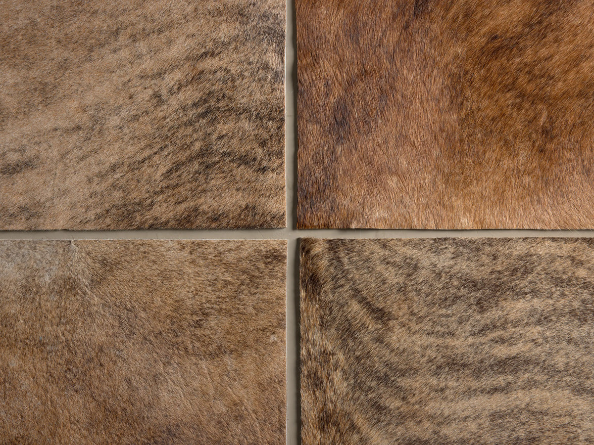 Tilton Hair on Hide Ottoman in blonde brindle, featuring rich brown and tan fur with dark stripes and visible seams.