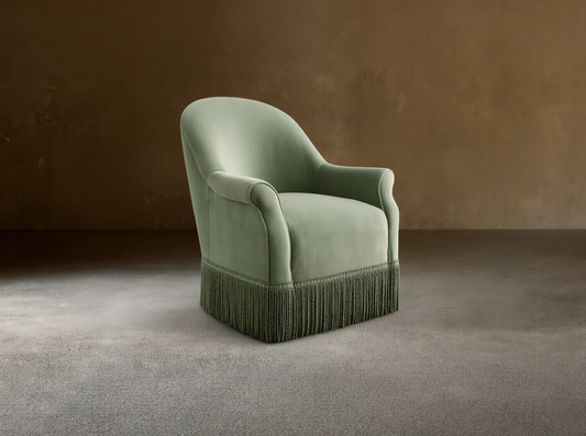 Front view of the sage green Augustus Swivel Chair with Fringe, featuring a rounded back, rolled arms, and a thick green fringe base.