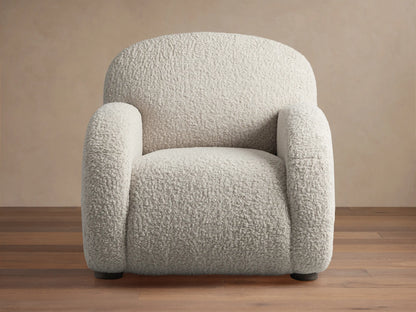 Algiers Chair, a plush off-white textured armchair with rounded arms and back, shown on a wooden floor.