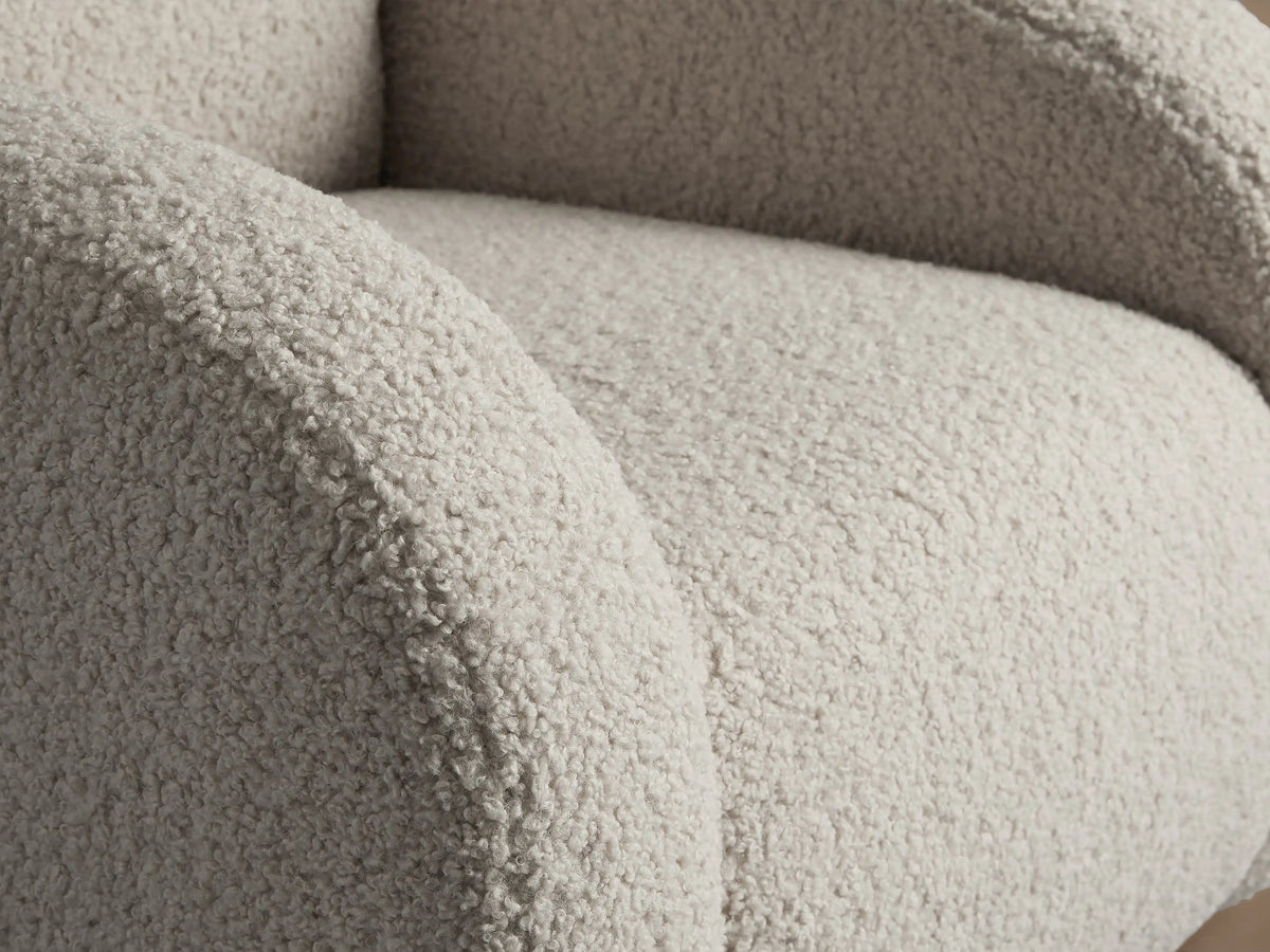 Close-up of the Algiers Chair upholstered in a creamy, textured bouclv© fabric, showing the curved armrest and seat.