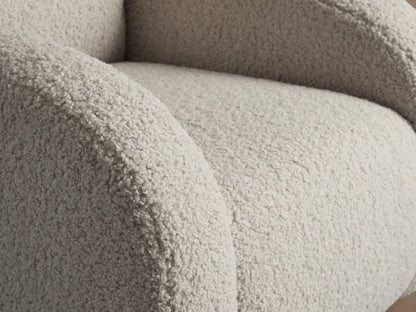 Close-up of the Algiers Chair upholstered in a creamy, textured bouclv© fabric, showing the curved armrest and seat.
