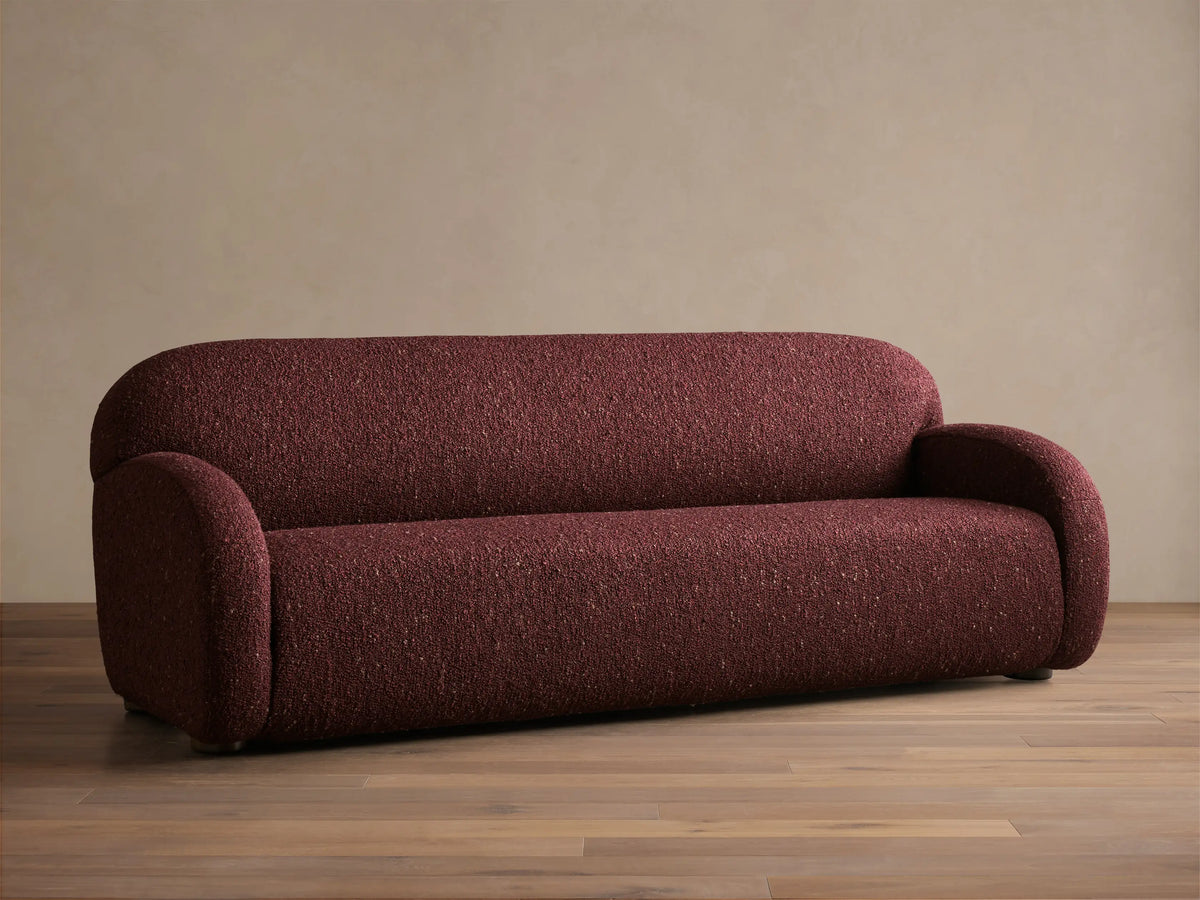 Front view of the deep red speckled Algiers Sofa, featuring rounded arms and a sleek, low-profile design.