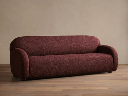 Front view of the deep red speckled Algiers Sofa, featuring rounded arms and a sleek, low-profile design.