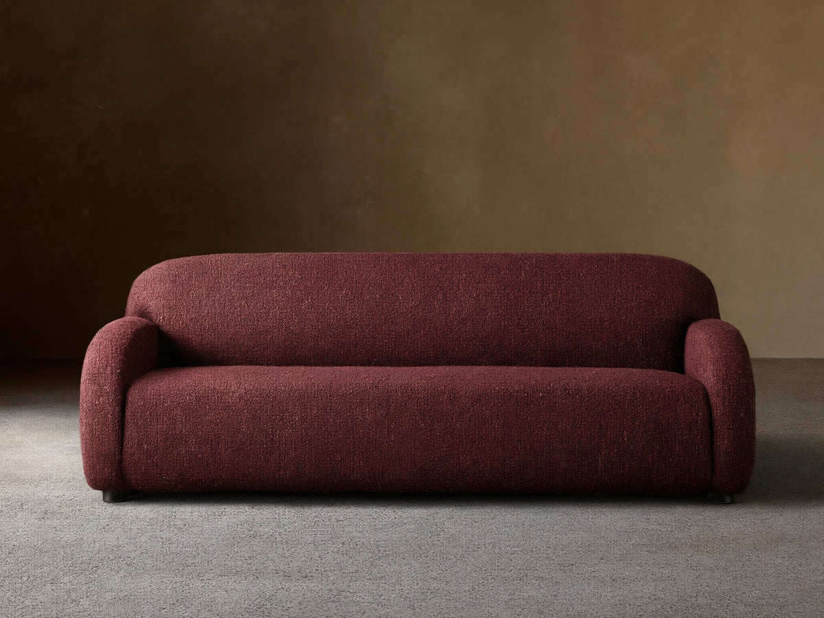 Front view of the deep red speckled Algiers Sofa, featuring rounded arms and a sleek, low-profile design.