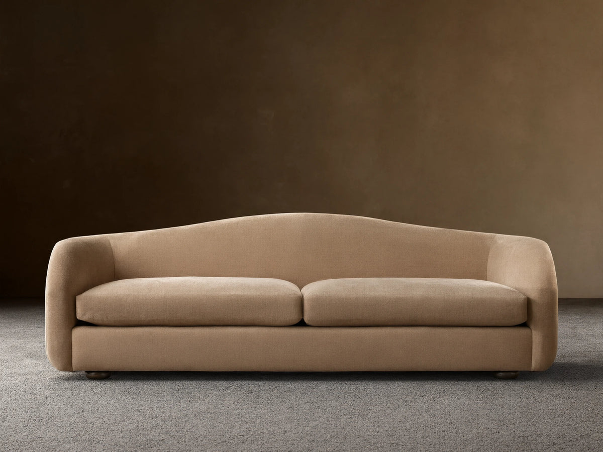 Ashlyn two-seat sofa with a curved back and integrated arms, upholstered in a light tan textured fabric.