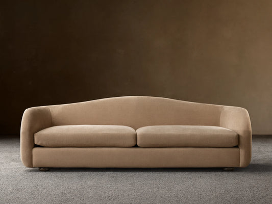 Ashlyn two-seat sofa with a curved back and integrated arms, upholstered in a light tan textured fabric.