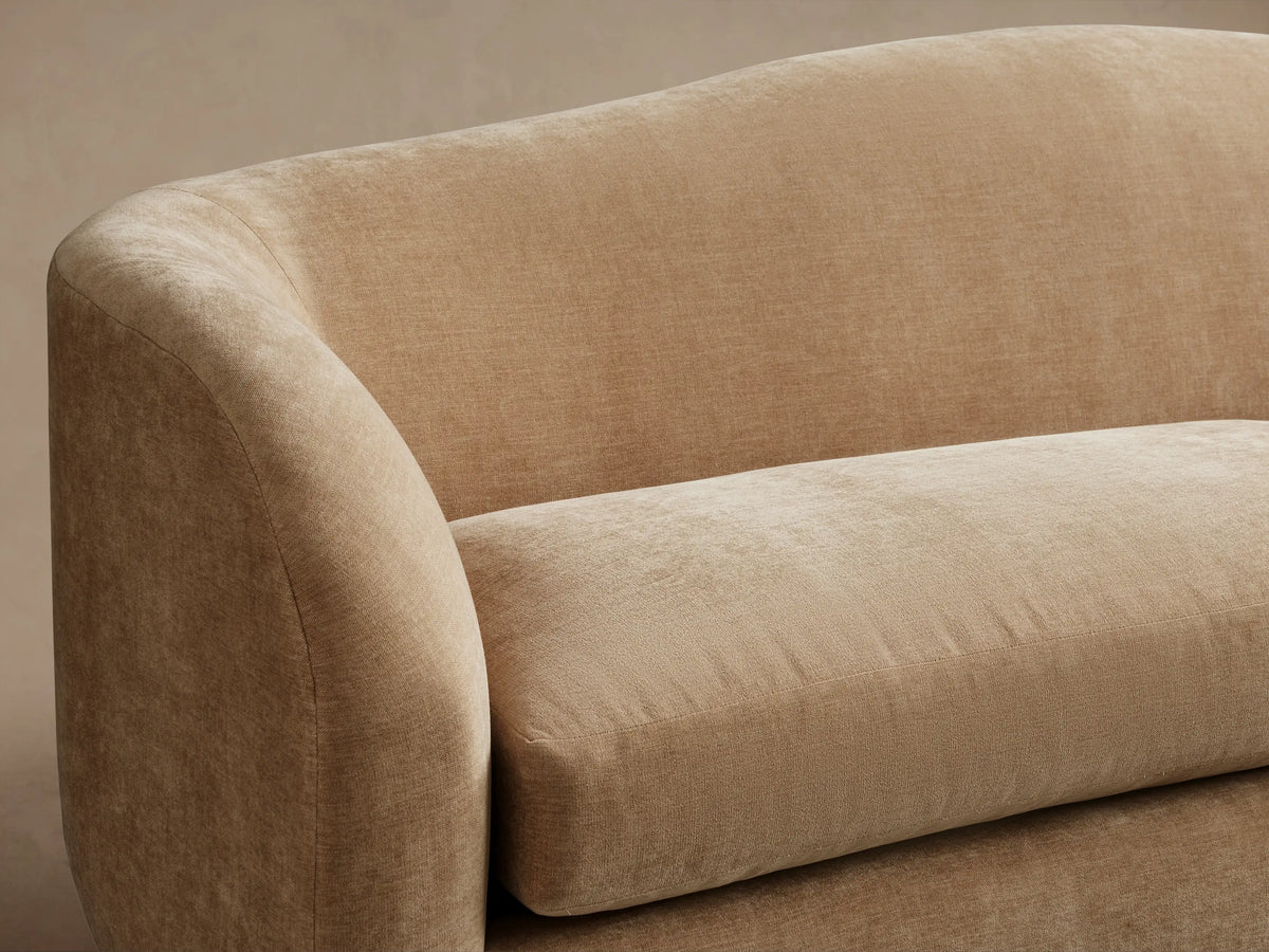 Ashlyn Two-Seat Sofa in light beige upholstered fabric, featuring a curved back and two soft seat cushions.