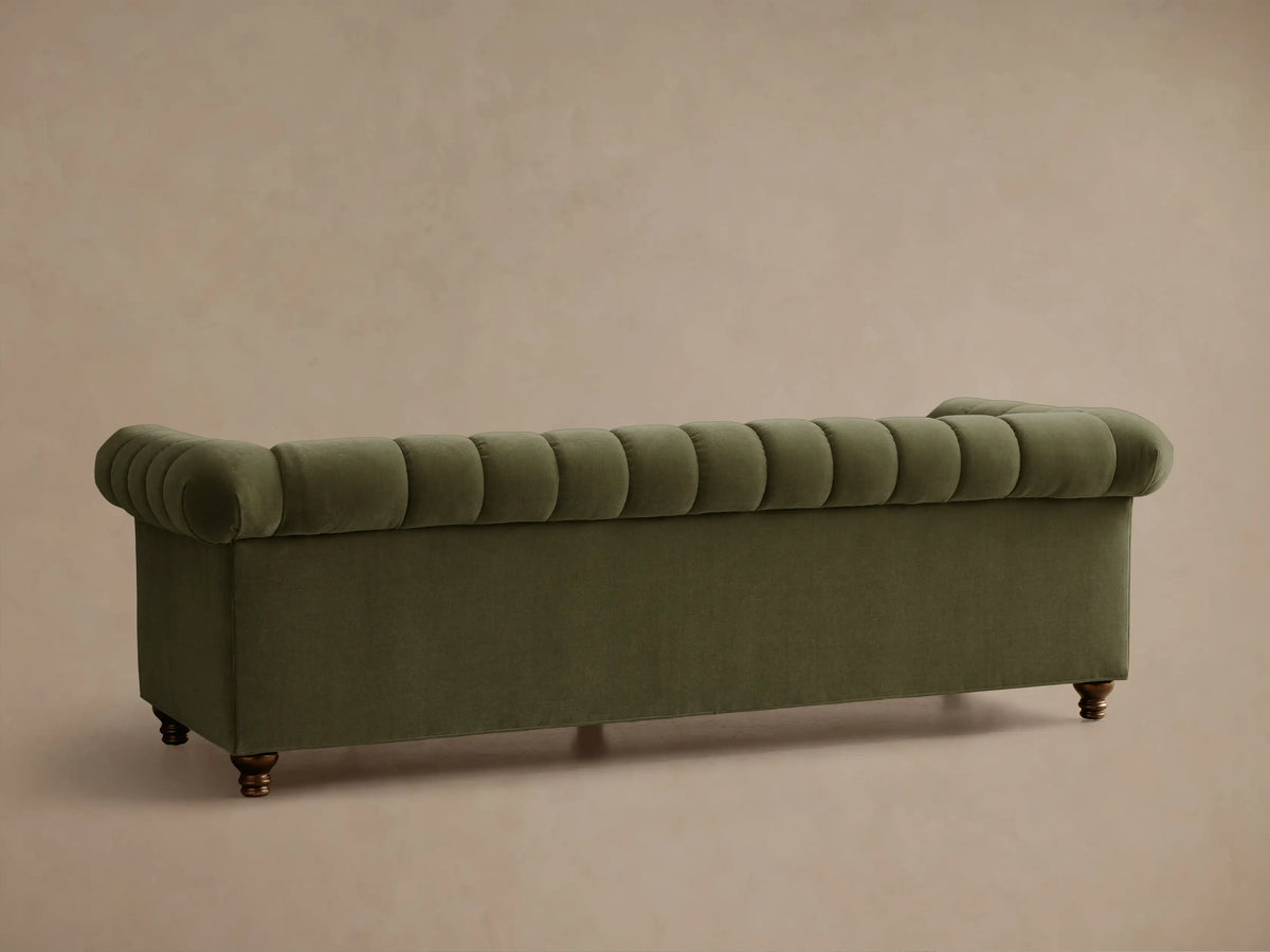 Angled view of an olive green Berwick Channeled Sofa, showing vertical channeling on back and seat cushions, with a rolled arm.